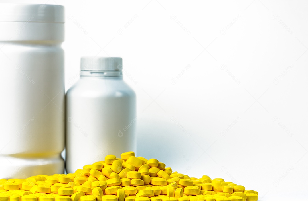 Pilha de comprimidos de comprimidos amarelos perto de frasco de comprimidos
