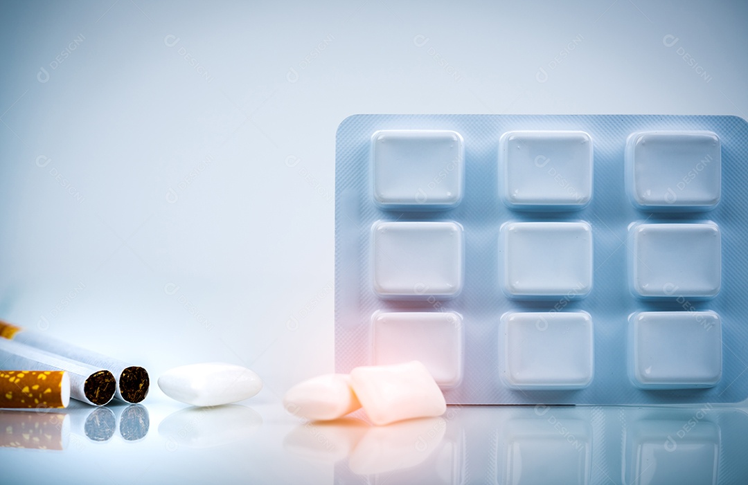 Goma de mascar de nicotina em blister perto de pilha de cigarro.