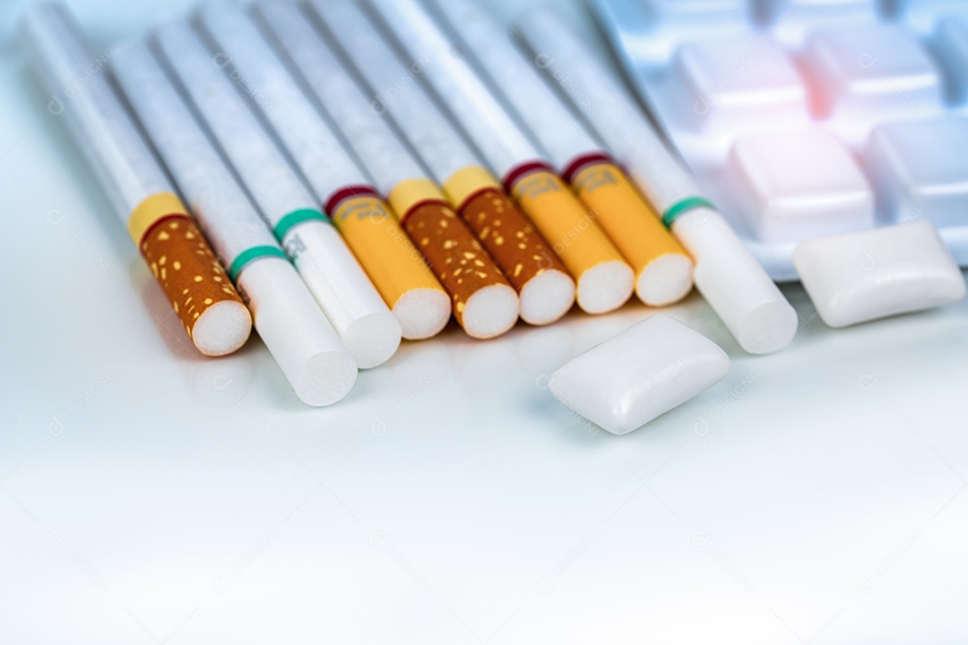 Goma de mascar de nicotina em blister perto de pilha de cigarro.