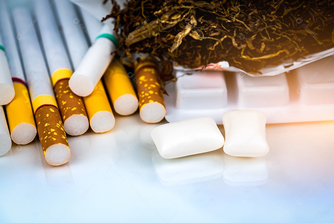 Goma de mascar de nicotina em blister perto de pilha de cigarro.