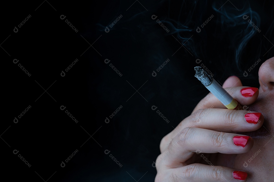 Mulher com unha vermelha está fumando cigarro em fundo escuro.