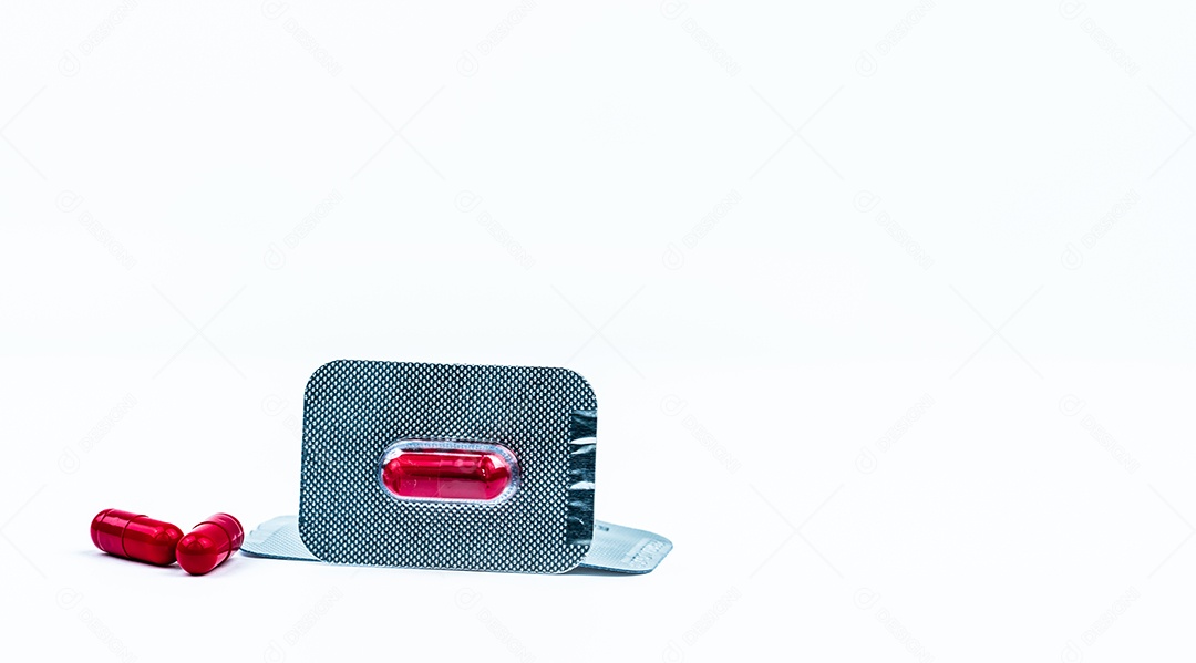 Cápsula vermelha em blister isolada no fundo branco.