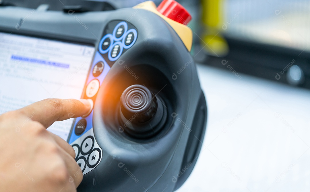 A mão do engenheiro aponta para o joystick do robô para controlar