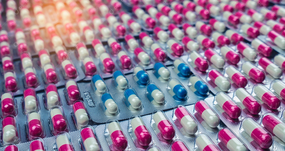 Closeup pílulas de cápsula de antibióticos rosa-branco e azul-branco