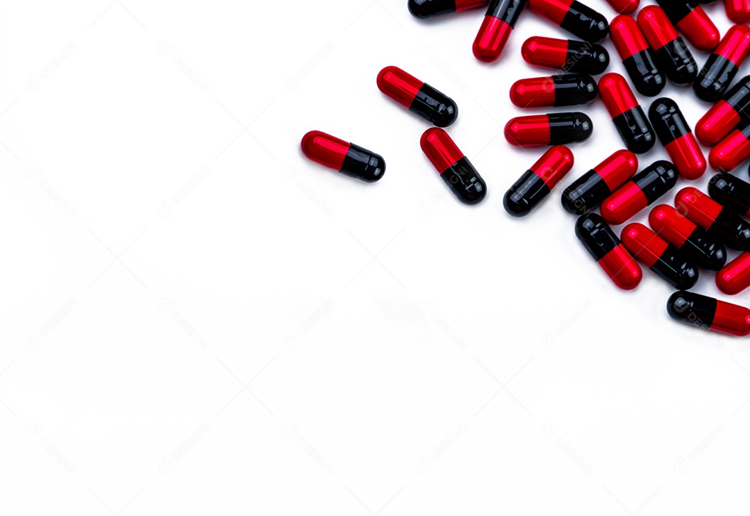 Comprimidos de cápsula vermelho-preto espalhados no fundo branco.