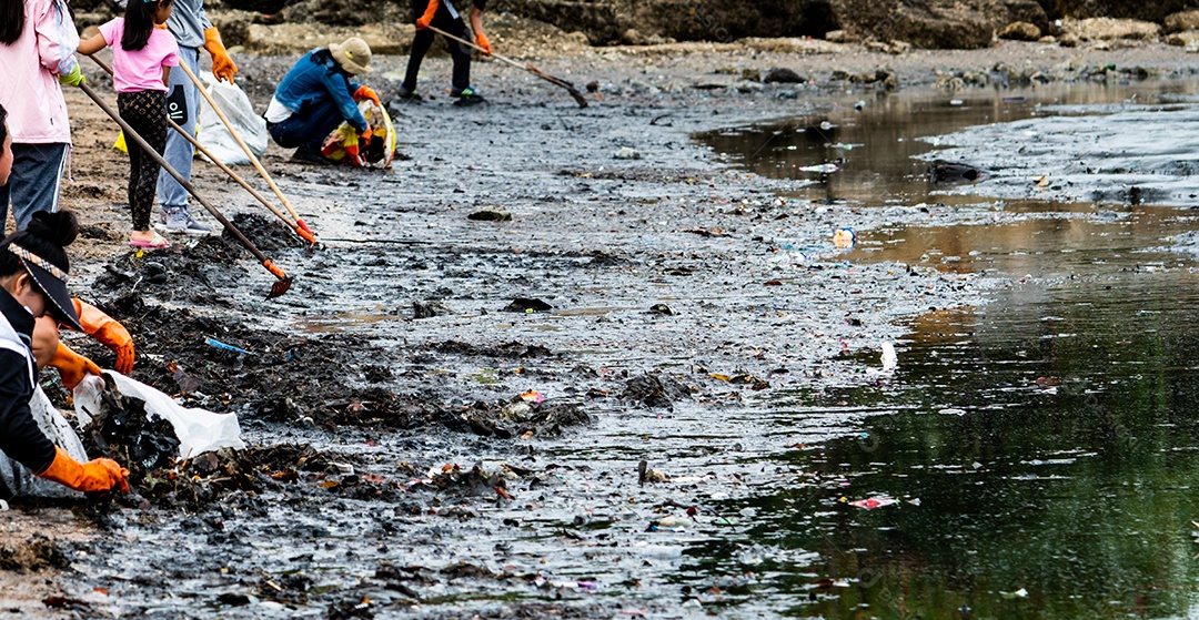 Voluntários adultos e crianças coletando lixo na praia do mar