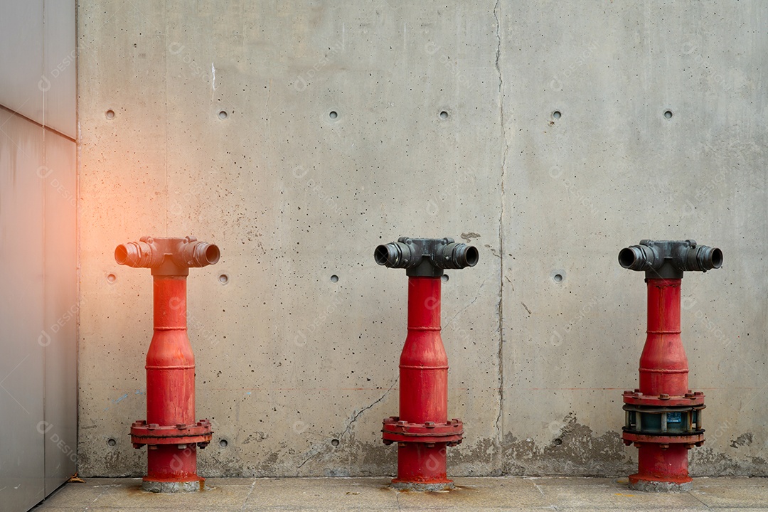 Três bombas de segurança contra incêndio no piso de cimento do edifício de concreto.