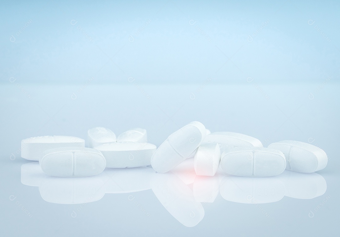 Pilha de comprimidos comprimidos oblongos brancos sobre fundo cinza.