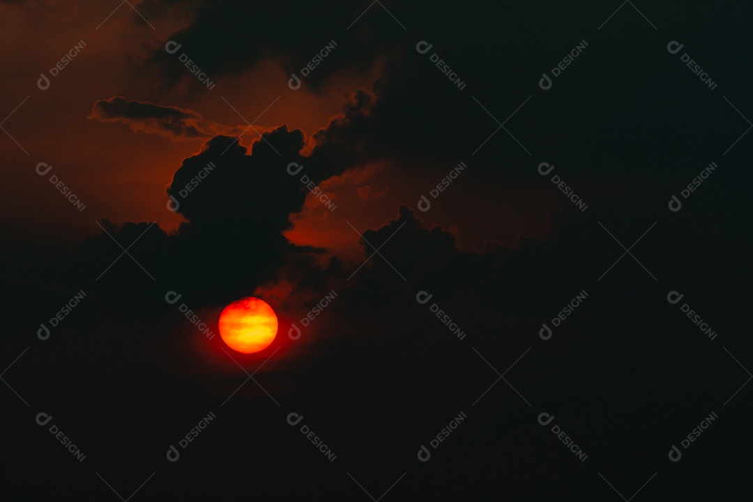 Sol grande vermelho em nuvens escuras. Pôr do sol do diabo.