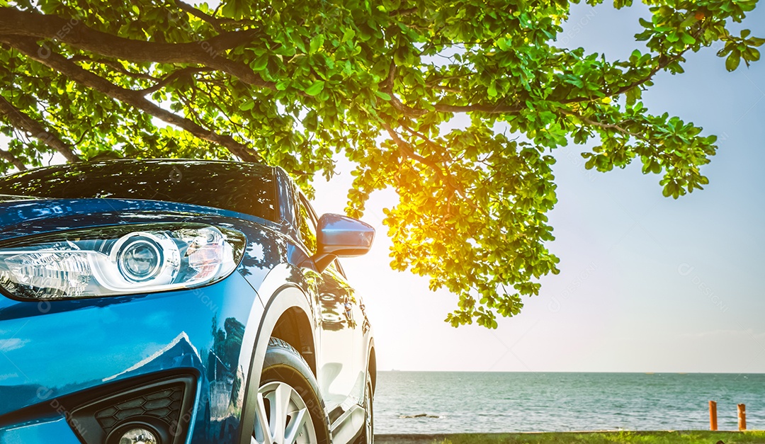 Carro esportivo azul SUV estacionado no mar tropical sob a árvore guarda-chuva