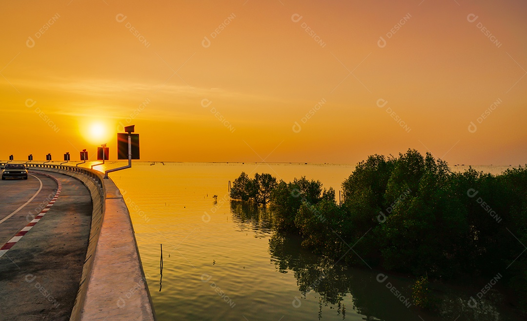 Estrada costeira curva e carro com céu laranja ao pôr do sol