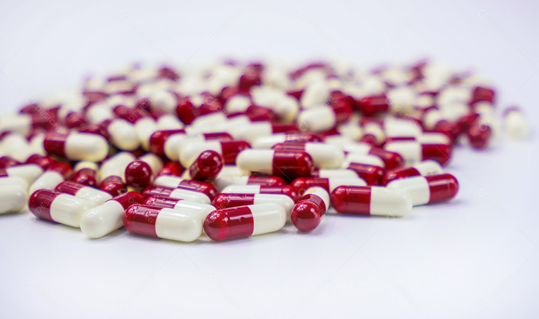 Comprimidos vermelhos e brancos da cápsula do foco seletivo no fundo branco.