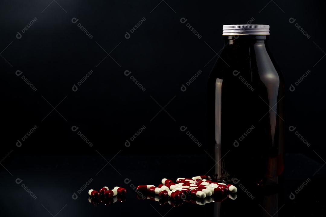 Comprimidos de cápsulas antimicrobianas vermelhas e brancas e frasco de vidro âmbar