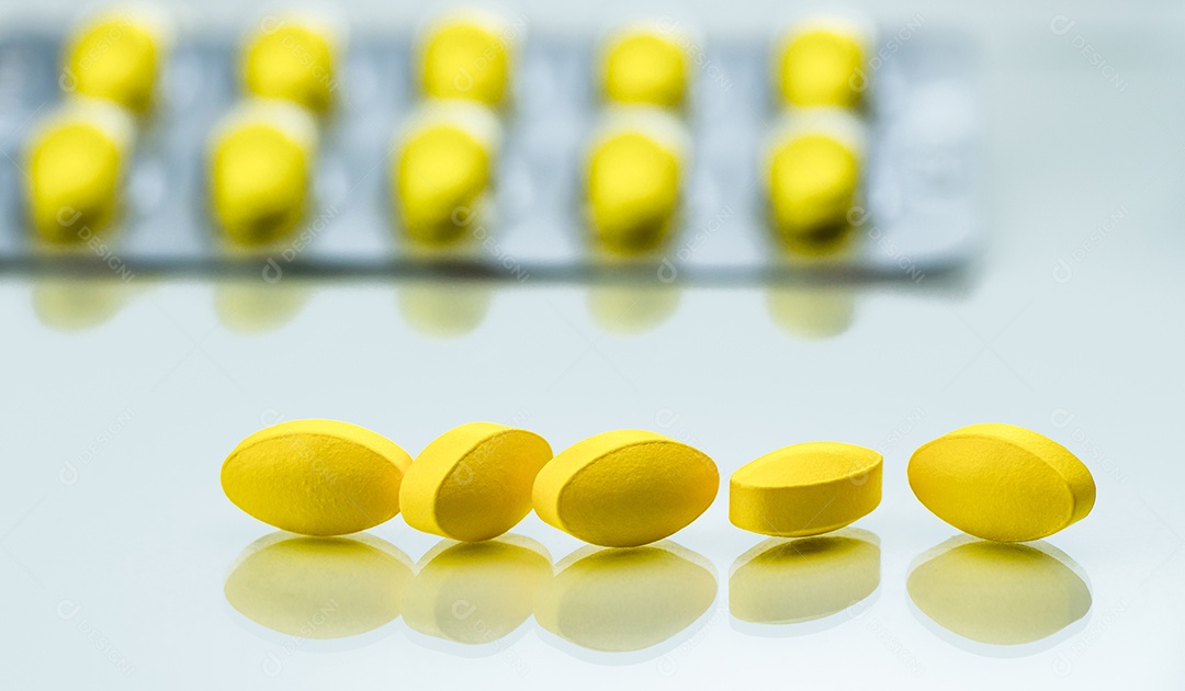 Detalhe de tiro macro de comprimidos ovais amarelos em fundo branco