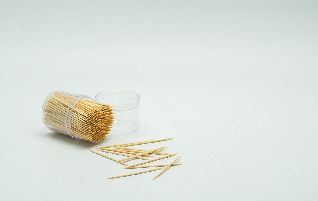 Palitos de dente em uma garrafa de plástico transparente. E alguns caíram no chão, palito inclinado, palito respingado