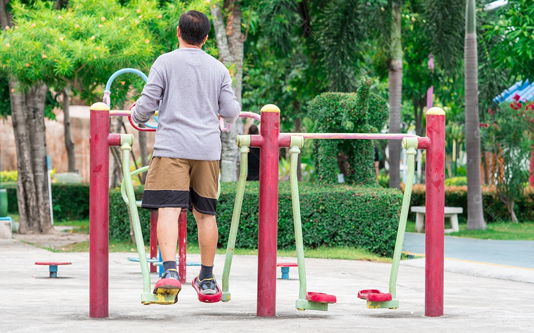 Homem adulto asiático usa camisa de manga longa e shorts se exercitando ao ar livre no parque pela manhã