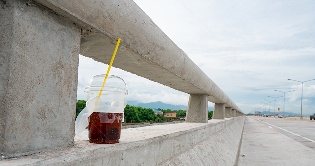 Caneca de plástico e tubo amarelo são colocados em pontes de concreto, com fundo de montanha e floresta de mangue