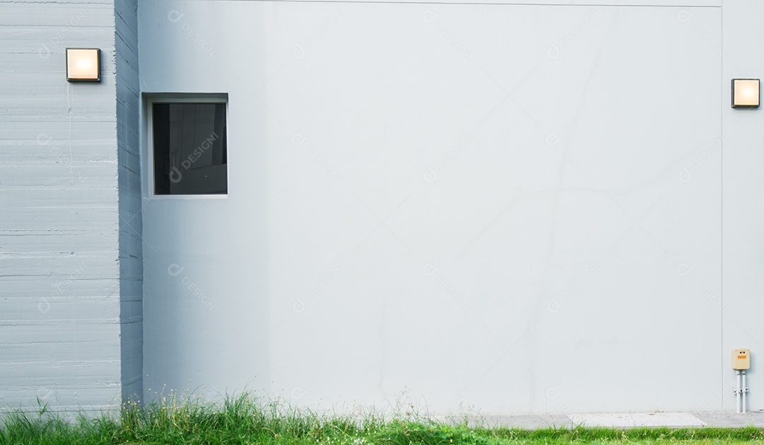 Parede de concreto cinza com lâmpada e grama verde na parte inferior