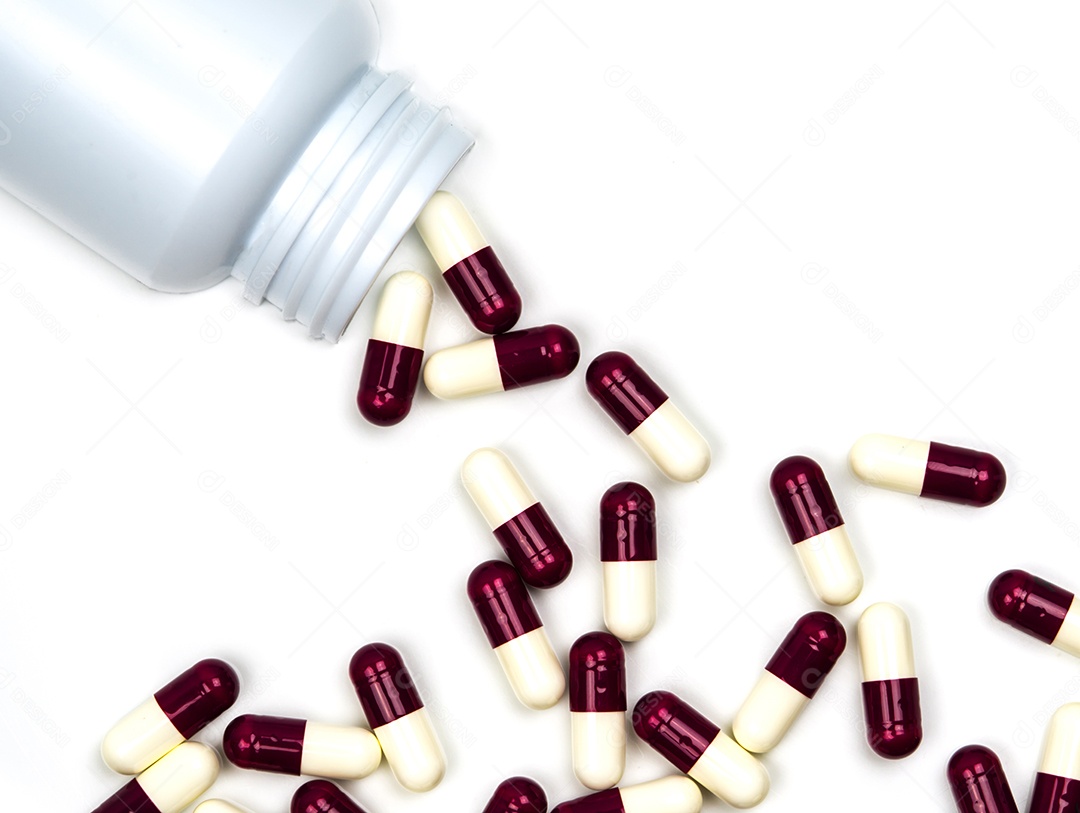 Comprimidos de cápsulas antibióticas derramando fora da garrafa de plástico