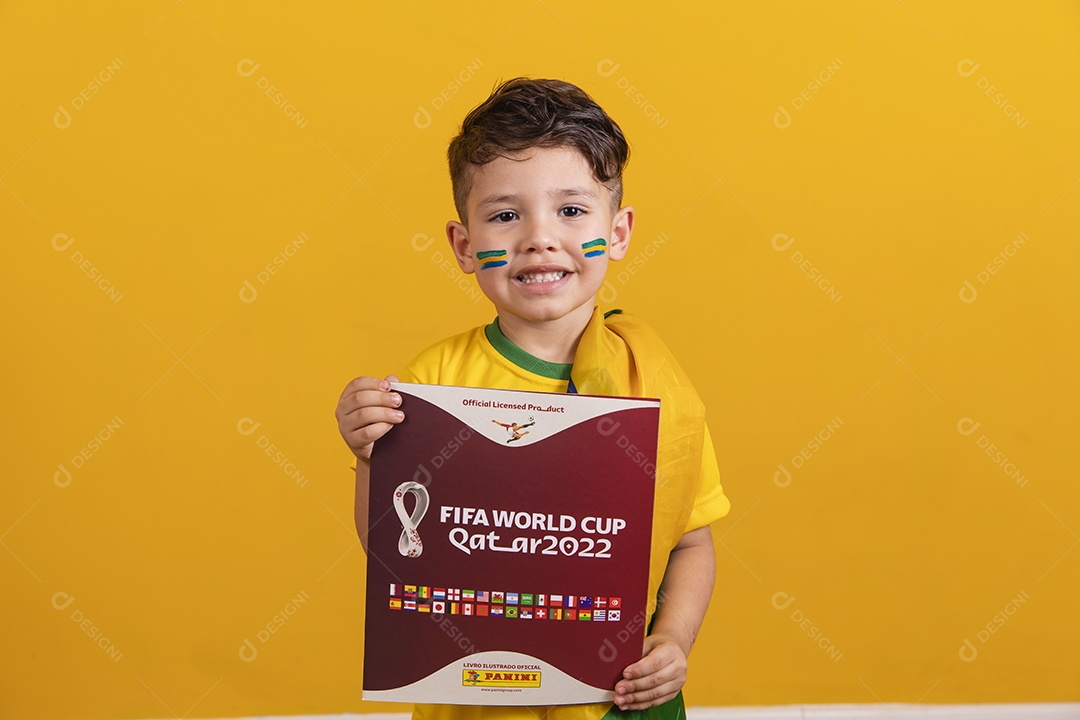Menino jovem criança brasileiro torcedor do brasil sobre fundo amarelo segurando álbum da copa do mundo