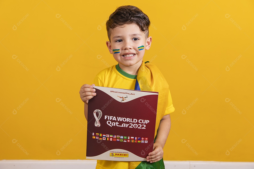 Menino jovem criança brasileira torcedor do brasil sobre fundo amarelo segurando álbum da copa do mundo