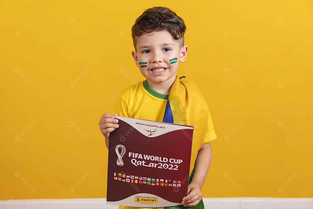 Menino jovem criança brasileiro torcedor do brasil sobre fundo amarelo segurando álbum da copa do mundo