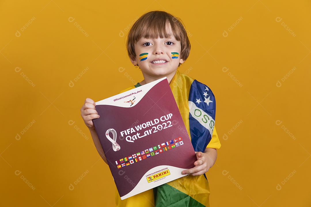 Menino jovem criança brasileira torcedor do brasil sobre fundo amarelo segurando álbum da copa do mundo