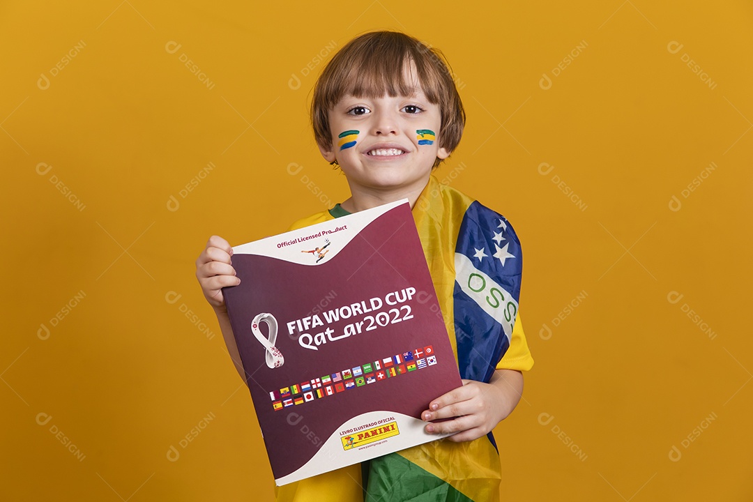 Menino jovem criança brasileira torcedor do brasil sobre fundo amarelo segurando álbum da copa do mundo