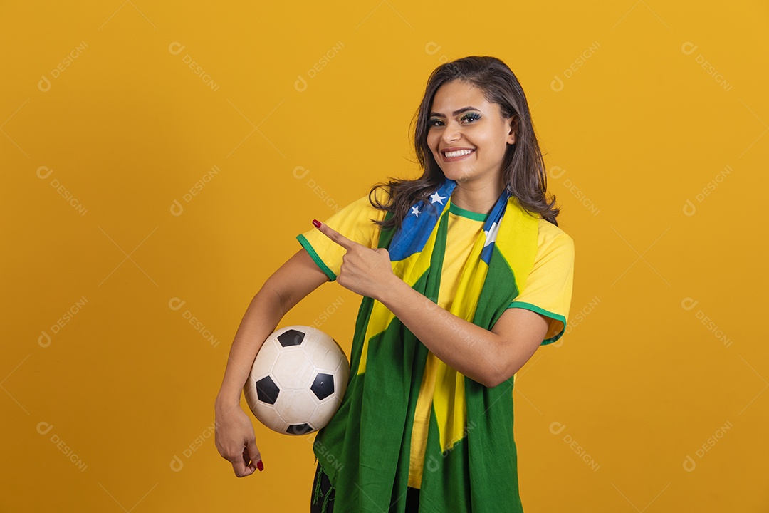 Linda mulher jovem brasileira garota torcedora do brasil segurando bola de futebol fundo amarelo