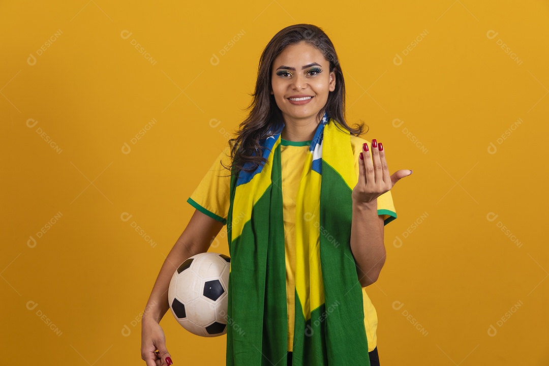 Linda mulher jovem brasileira garota torcedora do brasil segurando bola de futebol fundo amarelo