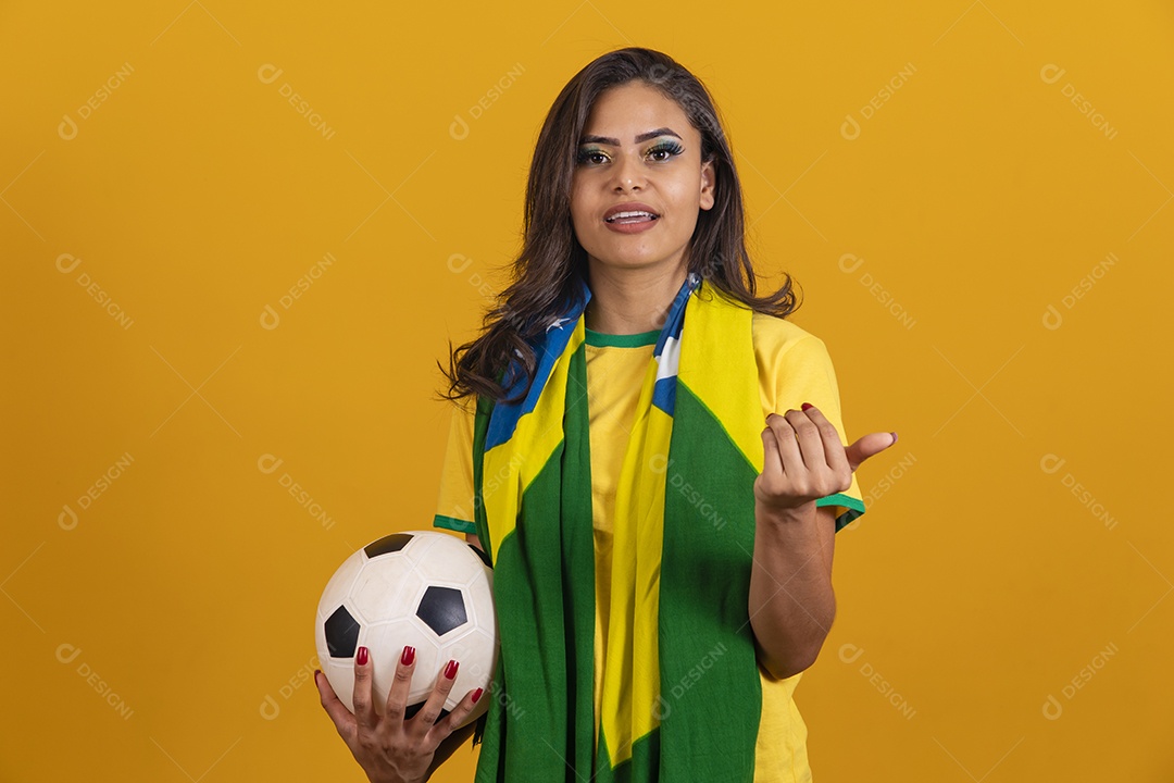 Linda mulher jovem brasileira garota torcedora do brasil segurando bola de futebol fundo amarelo