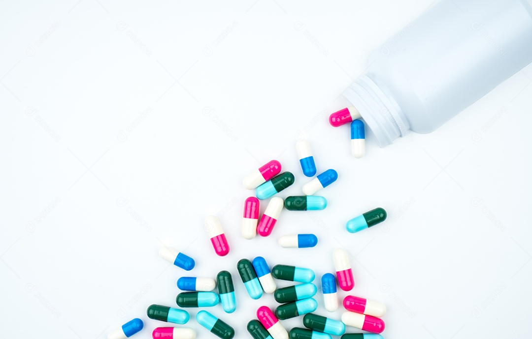 Cápsulas de antibióticos saindo do frasco de comprimidos em fundo branco com espaço de cópia