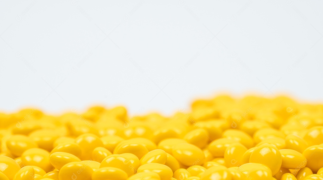 Comprimidos revestidos de açúcar amarelo em fundo branco com cópia