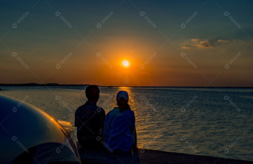 Silhueta de felicidade casal sentado e relaxando na praia