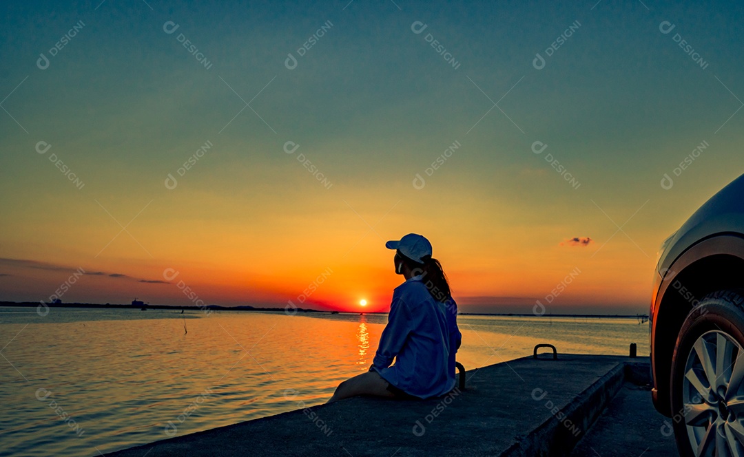 Uma jovem solitária usa um boné relaxando na praia sozinha em frente