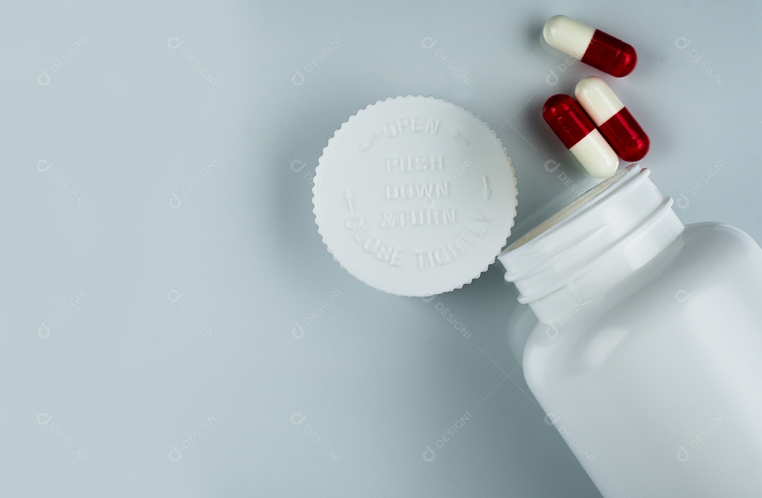 Comprimidos das cápsulas no fundo branco e na garrafa plástica com espaço em branco