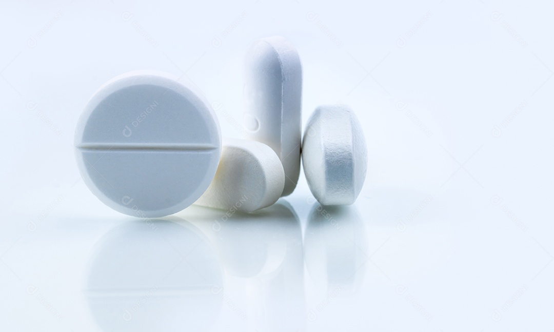 Pílulas brancas redondas e ovais em fundo branco.