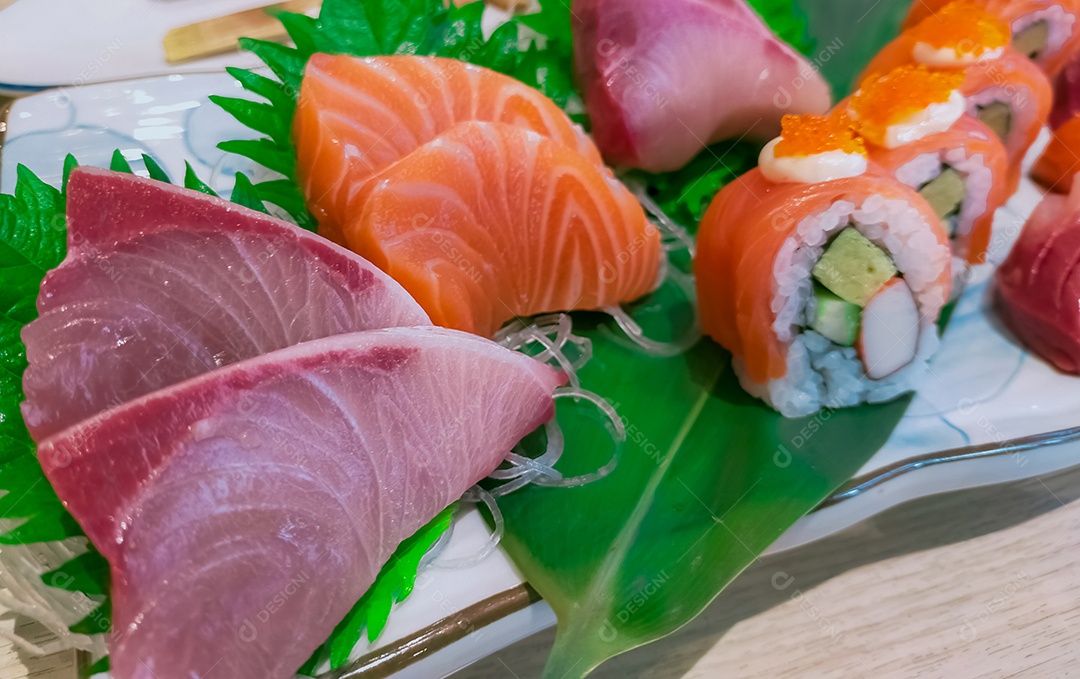 Comida japonesa servida em prato branco. Sushi e sashim de salmão