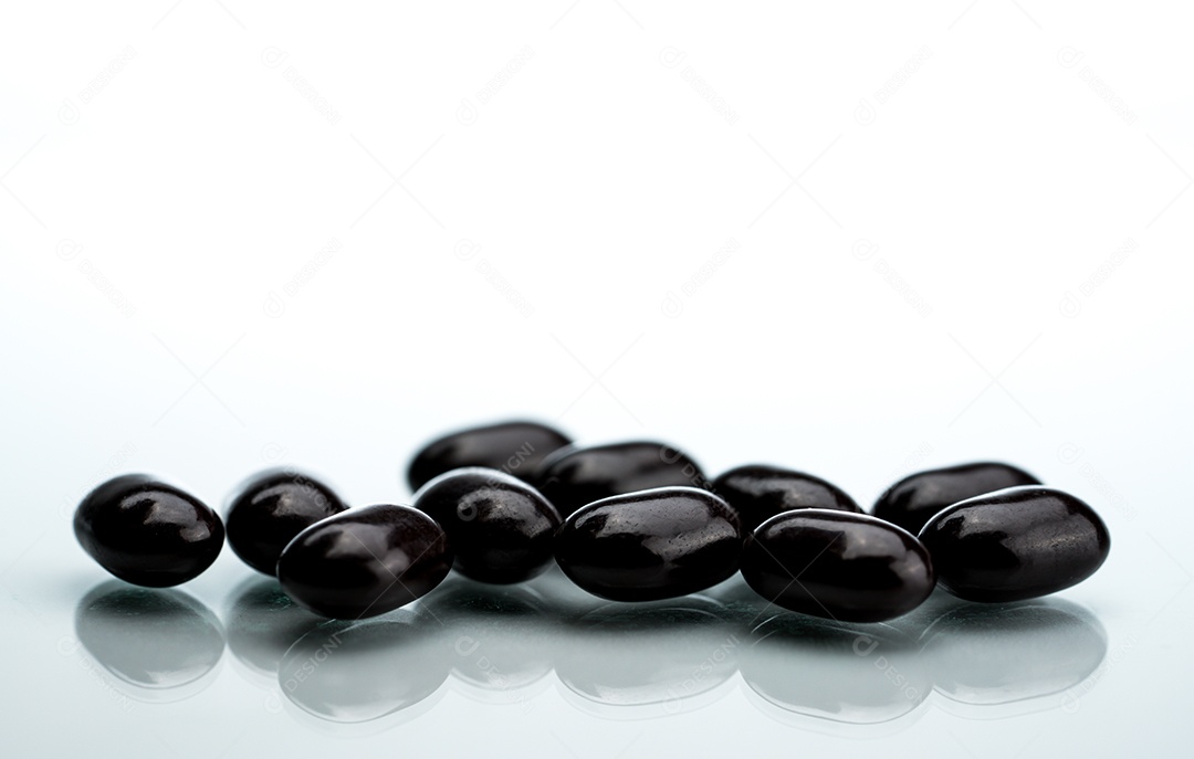 Comprimidos comprimidos pretos sobre um fundo branco. Vitaminas e minerais