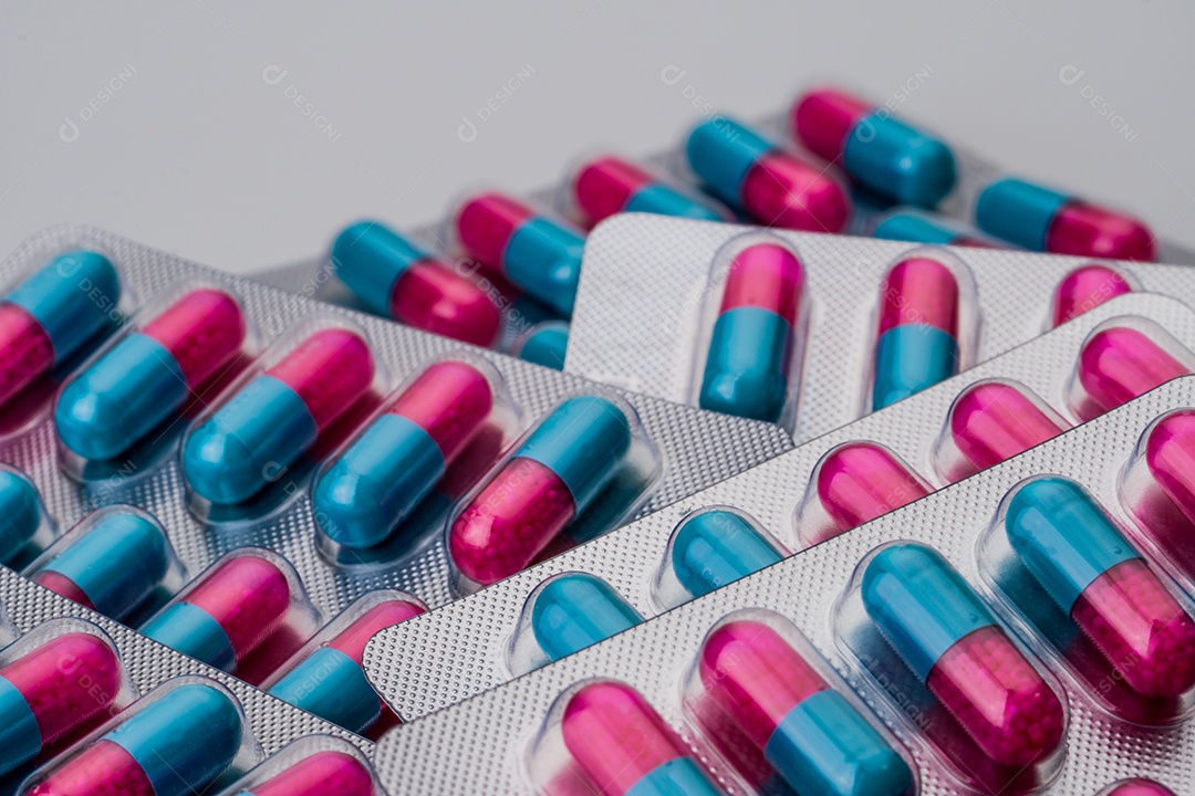 Pilha de cápsula azul e rosa com grânulo em pílulas laterais.