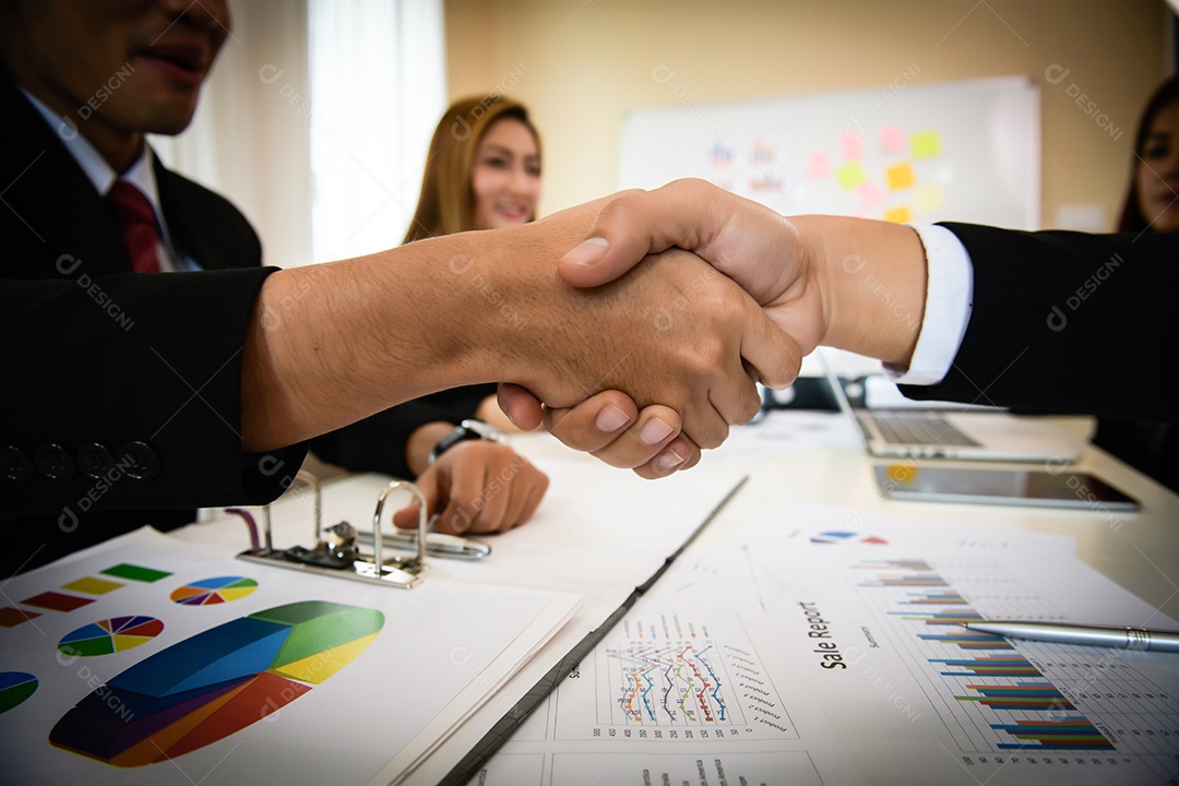 Pessoas de negócios apertando as mãos enquanto estão sentados no local de trabalho