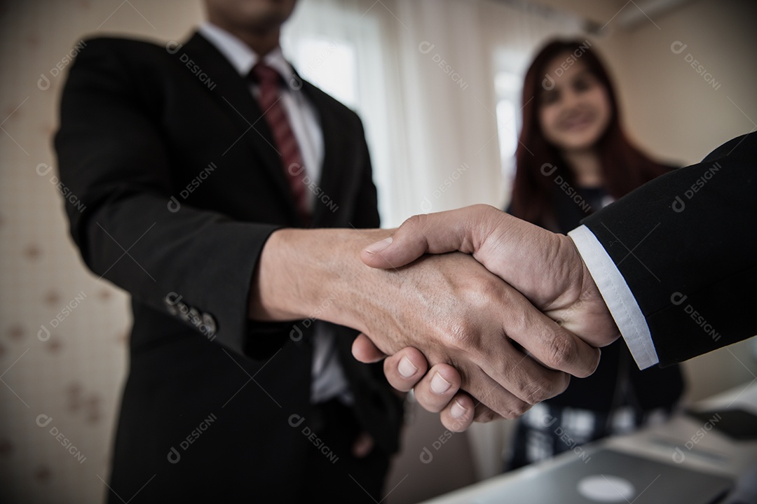 Pessoas de negócios apertando as mãos enquanto estão sentados no local de trabalho