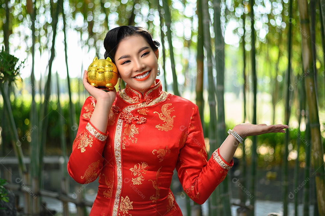 Retrato mulher asiática bonita em um cheongsam chinês posando com cofrinho e abra as palmas das mãos