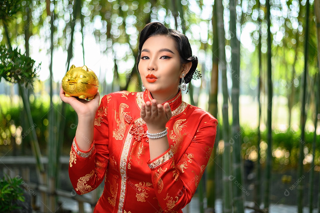 Retrato mulher asiática bonita em um cheongsam chinês posando com cofrinho e abra as palmas das mãos