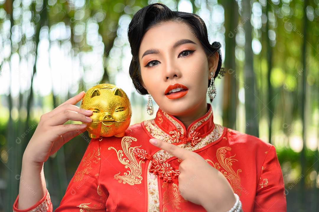 Retrato mulher asiática bonita em um cheongsam chinês posando com cofrinho e abra as palmas das mãos