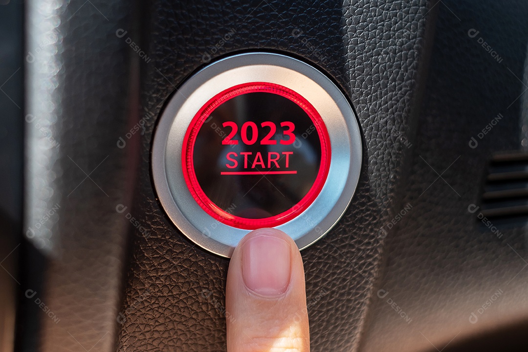 Finger press a car ignition button with the text START 2023 inside.