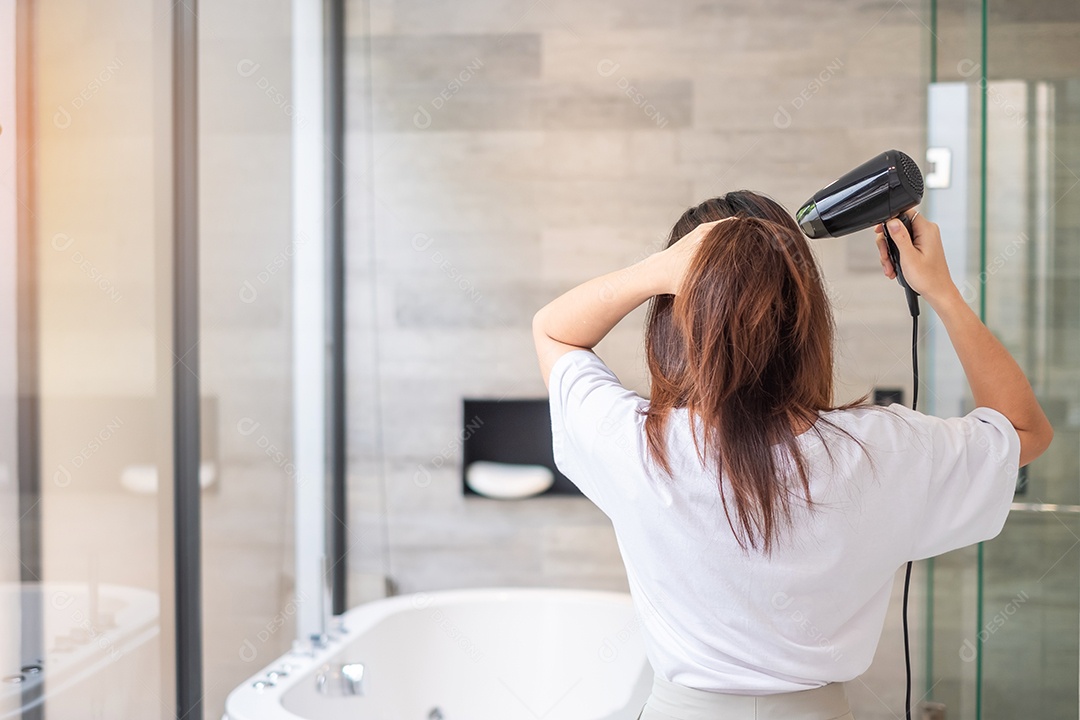 jovem usando secador de cabelo em casa ou hotel. Penteados