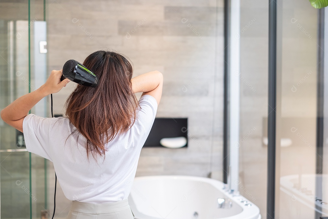 jovem usando secador de cabelo em casa ou hotel. Penteados