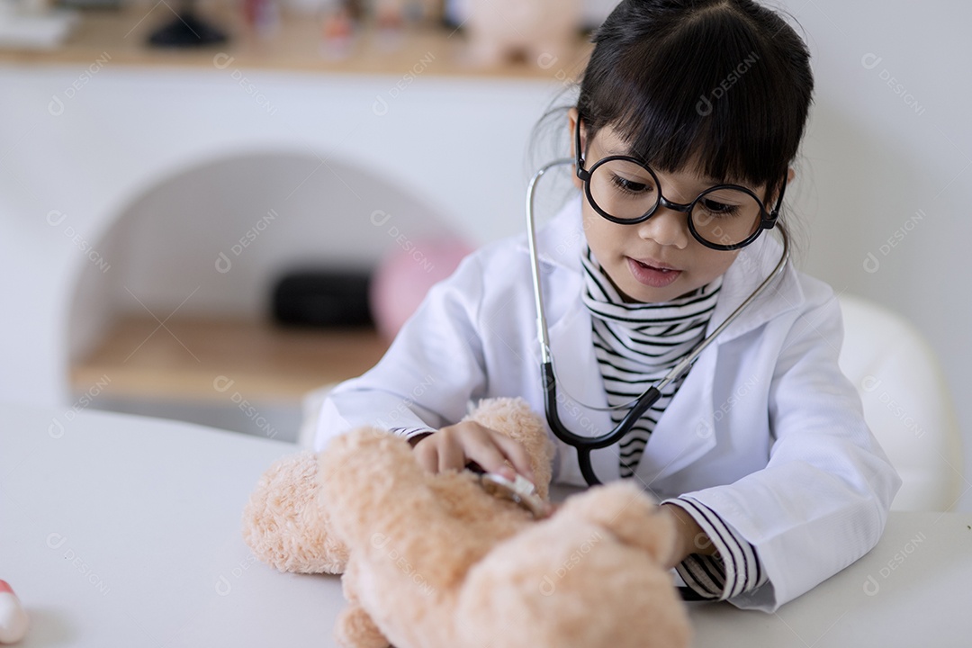 Menina asiática brincando com seu paciente urso de pelúcia em um jogo médico
