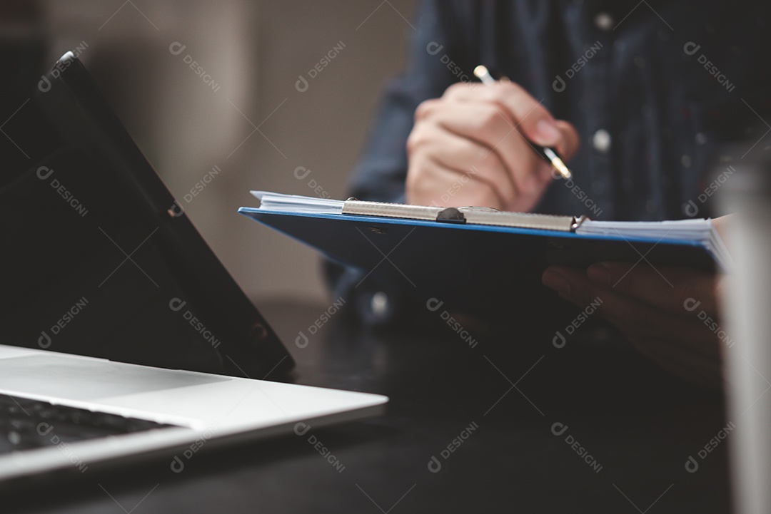 Mão segurando a caneta escrevendo papelada documento de negócios investimento financeiro ou trabalho de contrato de assinatura e seguro na mesa.